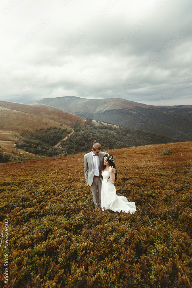 gorgeous bride and stylish groom walking,  boho wedding couple, luxury ceremony at mountains with amazing view, space for text