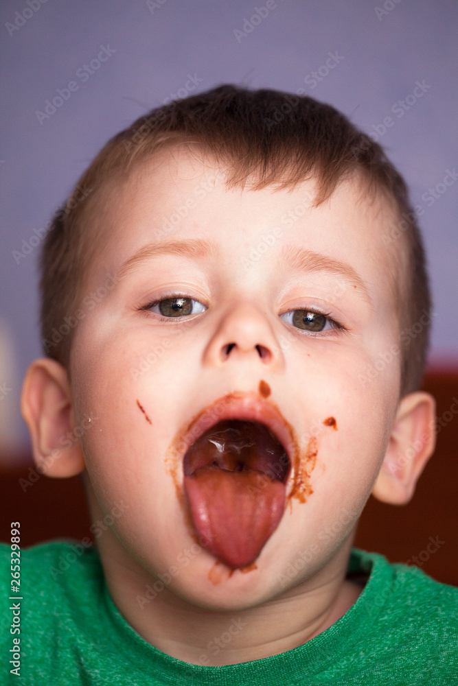 Close up portrait of Cute little boy eating chocolate yogurt at breakfast. Face messy with chocolate and naughty facial expression. Close up portrait of Cute little boy eating chocolate yogurt at breakfast. Face messy with chocolate and naughty facial expression.