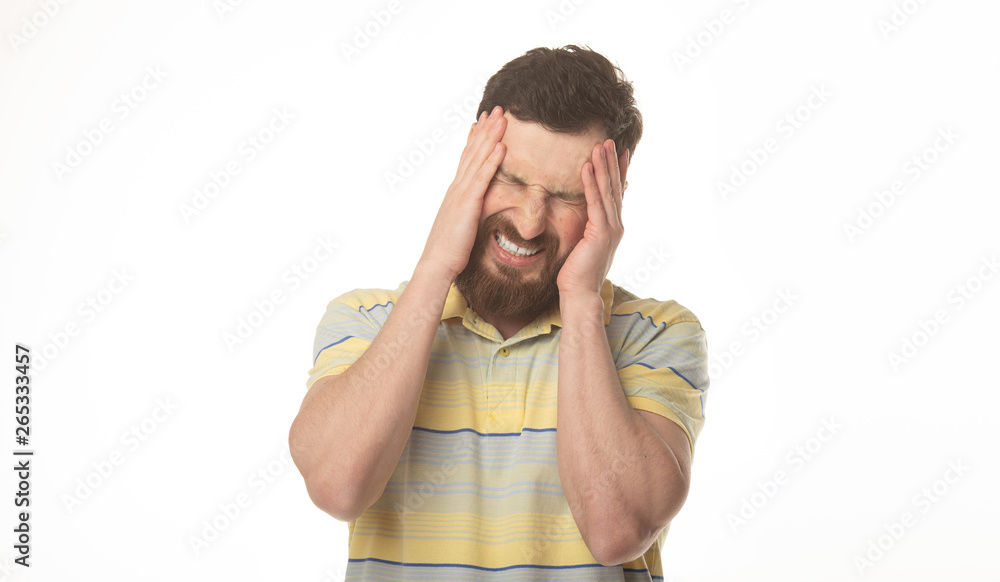 Feeling terrible headache. Portrait of bearded man is standing and touching his temples while suffering from pain. Feeling terrible headache. Portrait of bearded man is standing and touching his temples while suffering from pain.