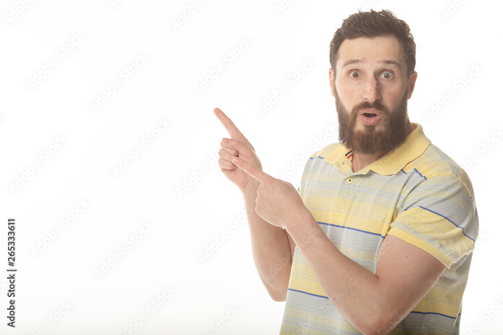 Young man in shirt pointing to the side with a finger to present a product or an idea while looking forward smiling on isolated white background Young man in shirt pointing to the side with a finger to present a product or an idea while looking forward smiling on isolated white background