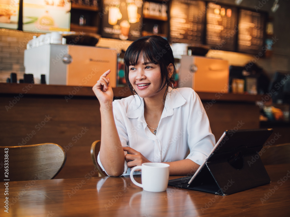 Asian woman drinking coffee in cafe and using laptop computer for working business online marketing Asian woman drinking coffee in cafe and using laptop computer for working business online marketing