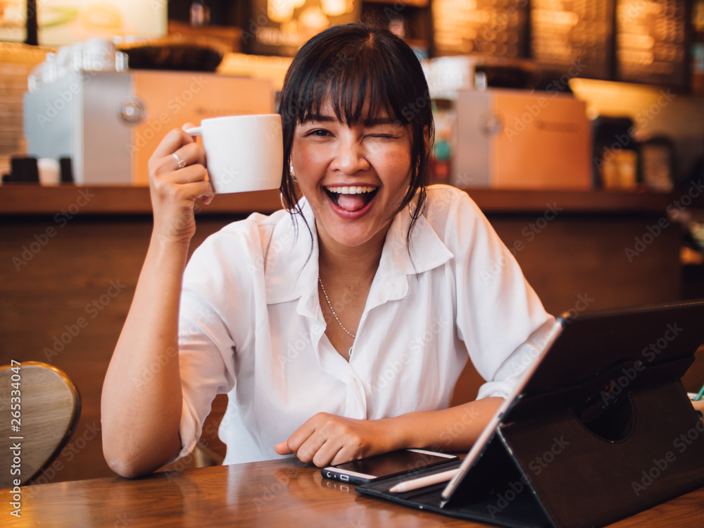 Asian woman drinking coffee in cafe and using laptop computer for working business online marketing Asian woman drinking coffee in cafe and using laptop computer for working business online marketing