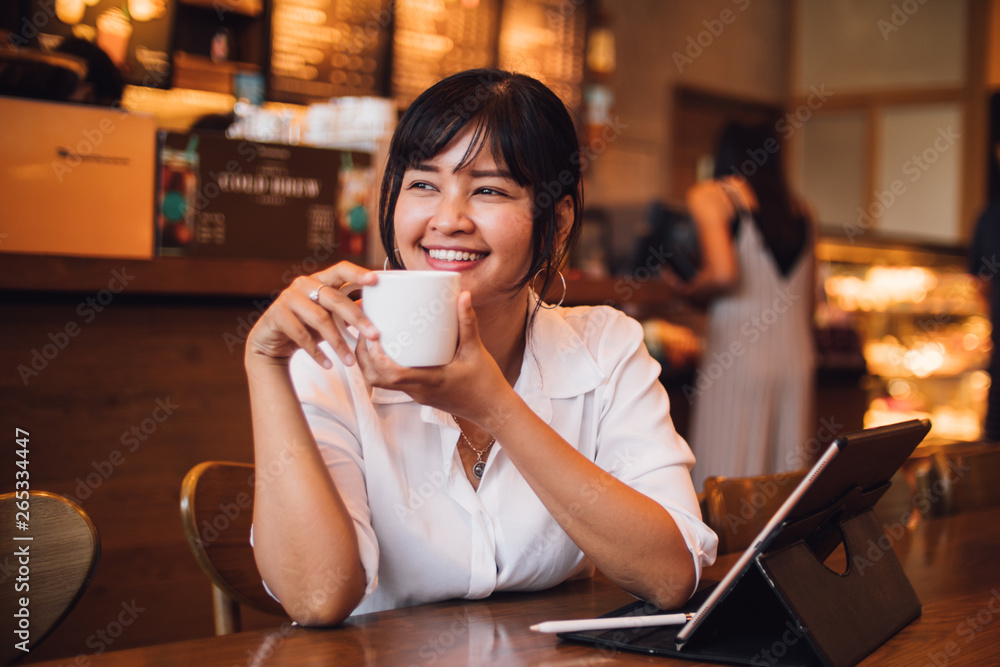 Asian woman drinking coffee in cafe and using laptop computer for working business online marketing Asian woman drinking coffee in cafe and using laptop computer for working business online marketing