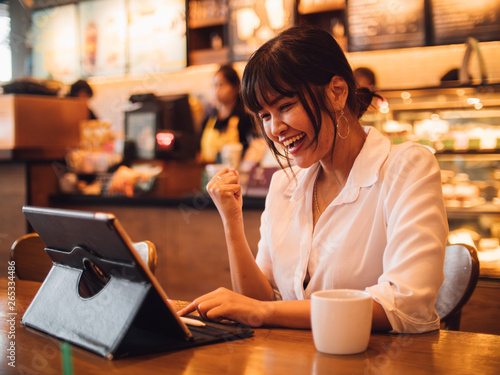 Asian woman drinking coffee in cafe and using laptop computer for working business online marketing