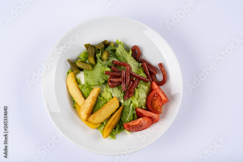 Grilled sausages, baked potatoes and vegetables on white plate