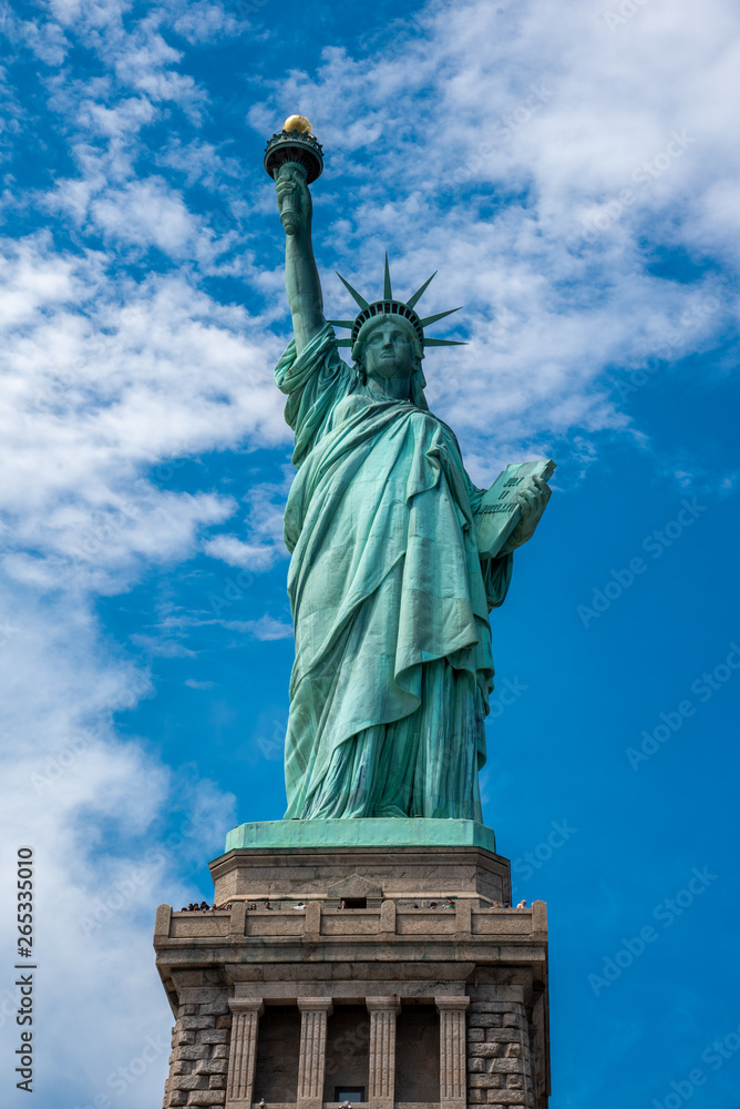 Obraz premium Shot of the Statue of Liberty in New York City, Usa. The shot is taken during a beautiful sunny day with a blue sky and white clouds in the background
