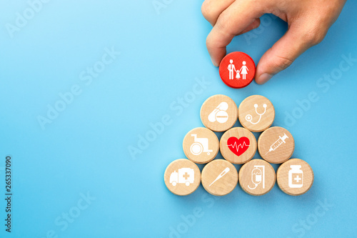 Fototapeta Naklejka Na Ścianę i Meble -  Health insurance concept, Hand holding a wood cubes with healthcare medical icon, blue background, copy space