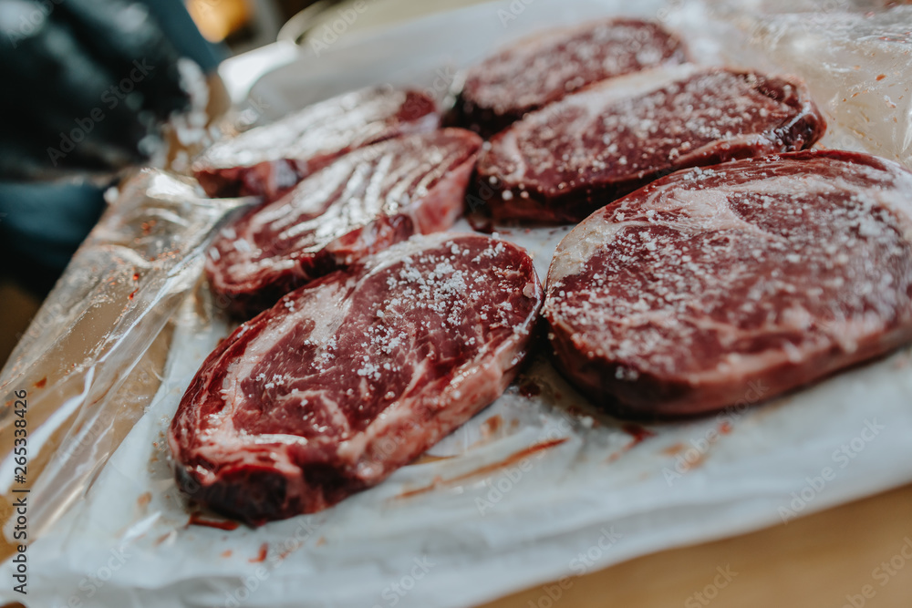 hands seasoning raw dry-aged Rib Eye Steaks hands seasoning raw dry-aged Rib Eye Steaks