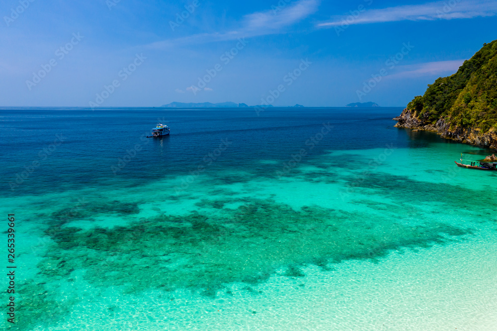 Fototapeta premium Aerial drone view of a boat moored off a beautiful, deserted tropical island