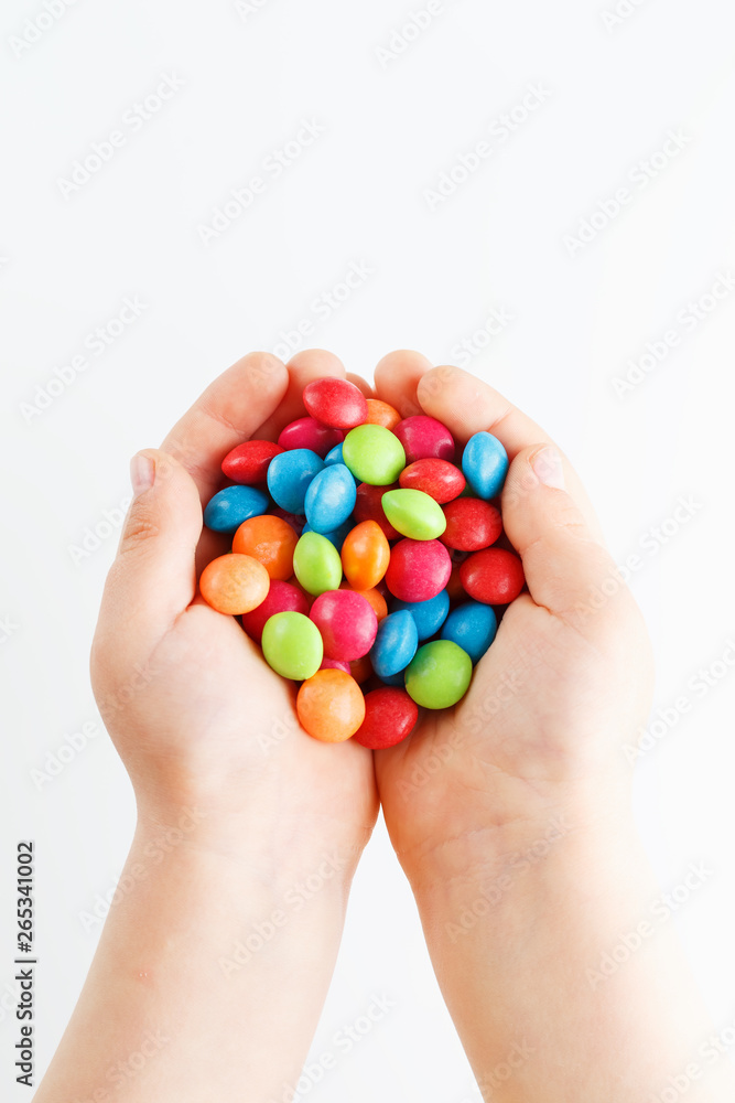 Multicolored candies in the hands of a child on a white isolated background Multicolored candies in the hands of a child on a white isolated background