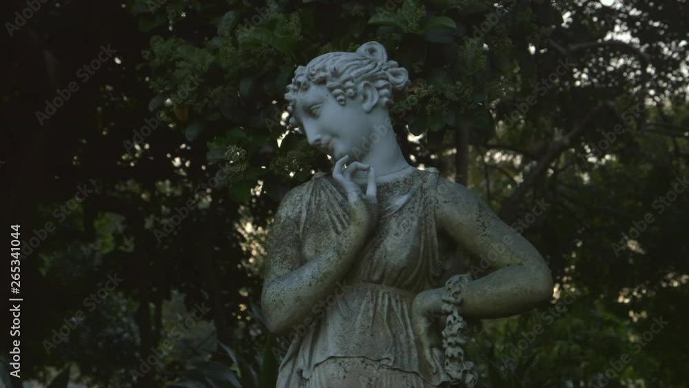 Slight panning from side to side using a medium shot of female garden statue.