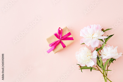 Flat lay composition with light pink peonies and gift box on a pink background © maria_lh