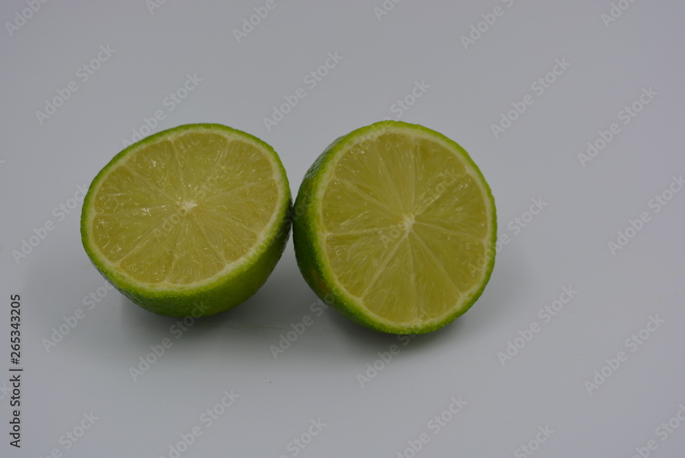Green sliced lime fruit in two equal even halves, fresh fruit, healthy food on a white background. Green sliced lime fruit in two equal even halves, fresh fruit, healthy food on a white background.