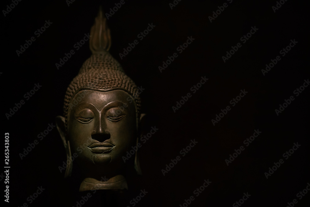 Head Buddha statue with aura used as amulets of Buddhism religion on black dark light and shadow background. soft focus Head Buddha statue with aura used as amulets of Buddhism religion on black dark light and shadow background. soft focus