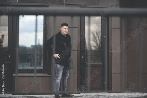 City Portrait of a young man in a jacket. Man standing in yard of city. Portrait of young man in casual clothes 