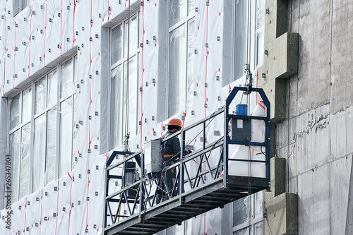 working in a hanging cradle at the construction site photo