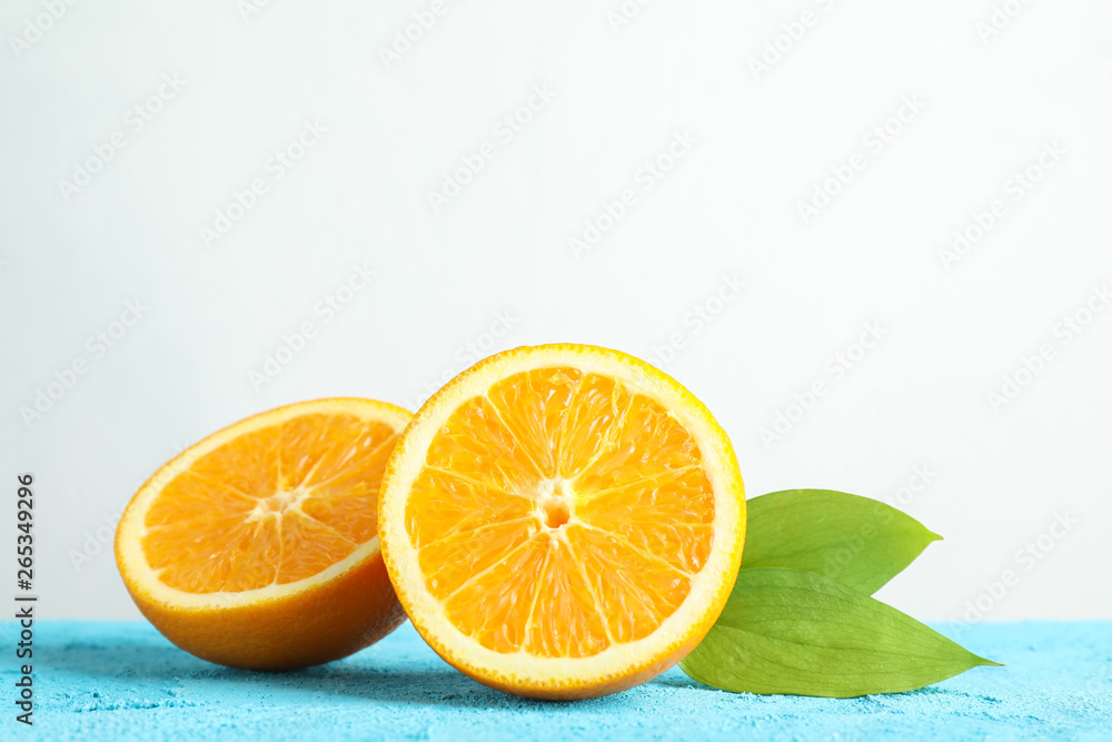 Halves orange with leaves on blue table against white background, space for text Halves orange with leaves on blue table against white background, space for text
