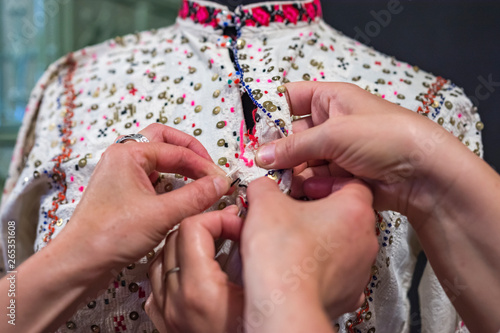 Traditional bulgarian clothes - materials and embroiders. Details of folk costume. Women's hand touching the textile.