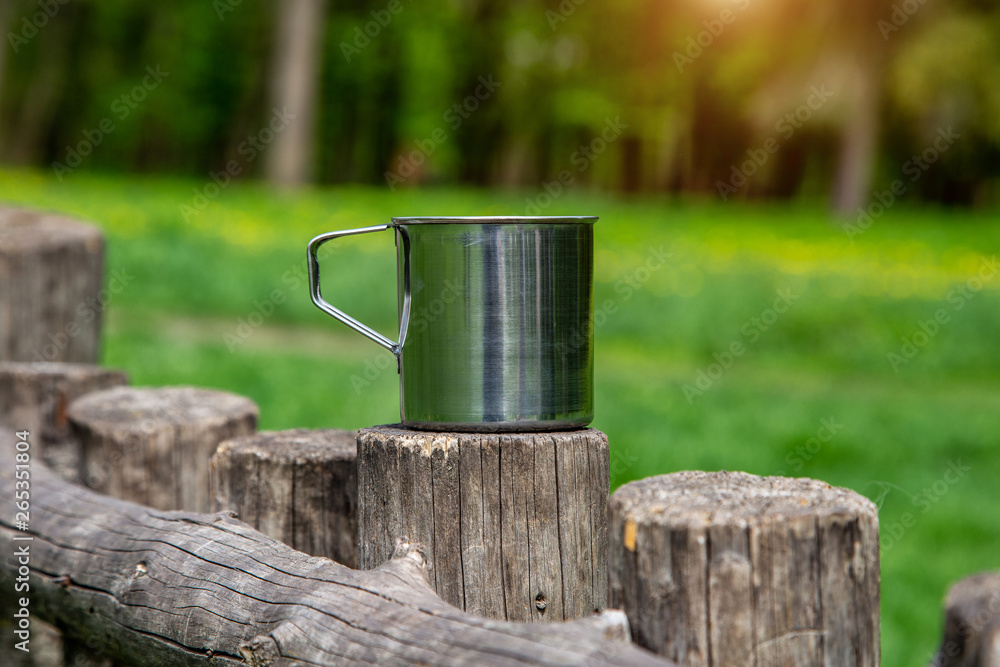 Tourist steel cup in the summer forest outdoors. Tourist steel cup in the summer forest outdoors.