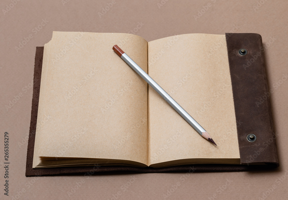 open craft notepad with leather cover and gray pencil on coffee background open craft notepad with leather cover and gray pencil on coffee background