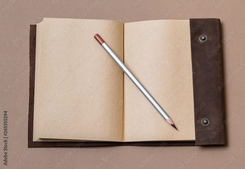 open craft notepad with leather cover and gray pencil on coffee background open craft notepad with leather cover and gray pencil on coffee background