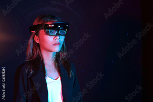 Business woman try vr glasses hololens in the dark room | Portrait of young asian girl experience ar | Future technology concept photo