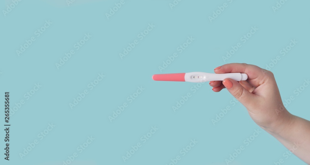 Unrecognizable woman holding a pregnancy test. Panoramic image with copy space. Unrecognizable woman holding a pregnancy test. Panoramic image with copy space.
