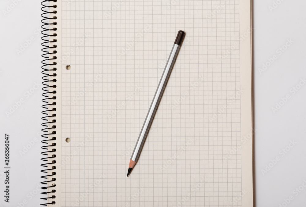white checked notebook and gray pencil on white background white checked notebook and gray pencil on white background