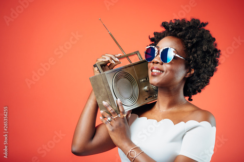 Black girl with sunglasses dancing to a hip song playing from the boombox photo