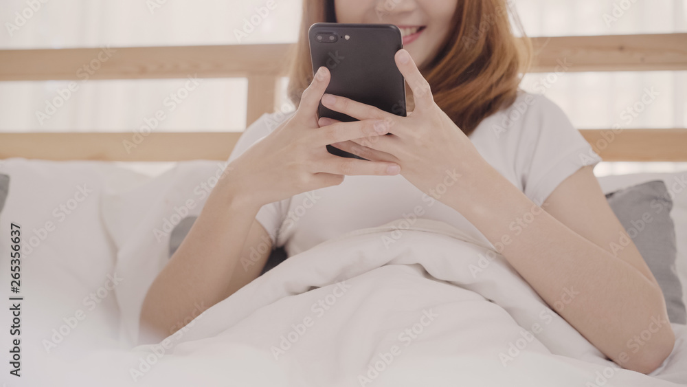 Young Asian woman using smartphone while lying on bed after wake up in the morning, Beautiful attractive Japanese girl smiling relax in bedroom at home. Enjoying time lifestyle women at home concept. Young Asian woman using smartphone while lying on bed after wake up in the morning, Beautiful attractive Japanese girl smiling relax in bedroom at home. Enjoying time lifestyle women at home concept.