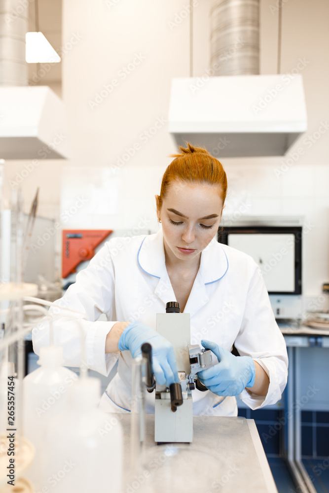 The girl in the lab looking through a microscope. The girl works in a scientific laboratory. The photo illustrates science and education. The girl in the lab looking through a microscope. The girl works in a scientific laboratory. The photo illustrates science and education.