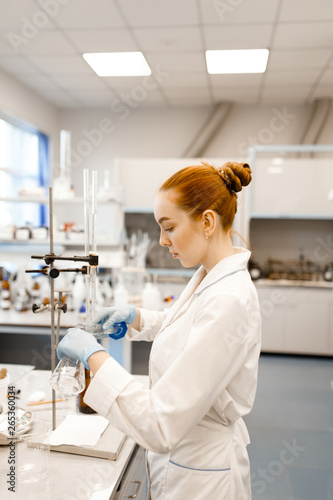 A young girl conducting experiments in a scientific laboratory. A young scientist in a modern laboratory. Student in the lab.