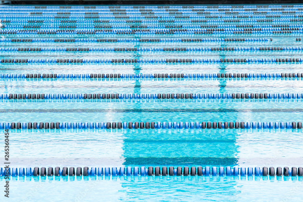 Lap lanes in an empty, calm blue swimming pool on a sunny afternoon.