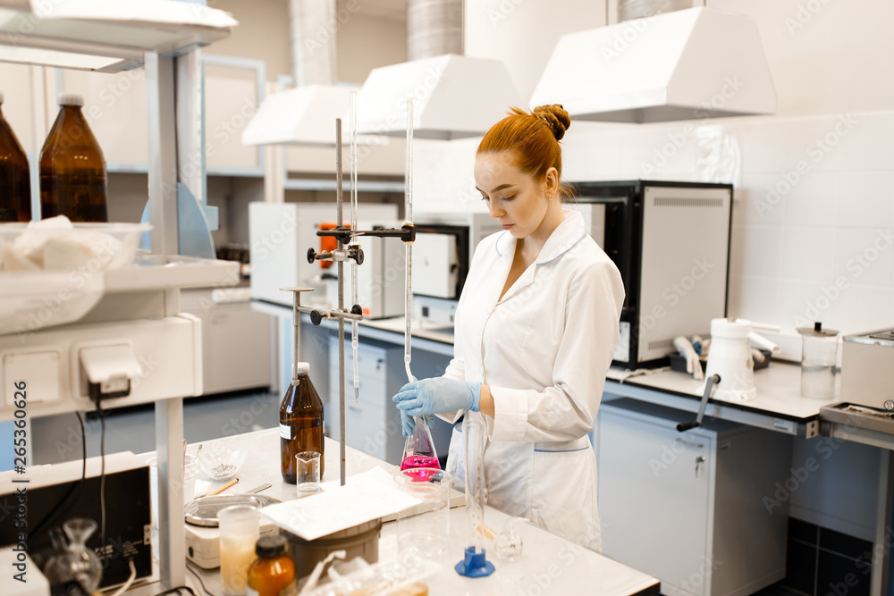 A young girl conducting experiments in a scientific laboratory. A young scientist in a modern laboratory. Student in the lab.