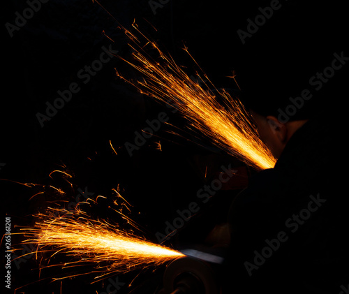 Fire sparks on a black background during workers sharpen a knife.