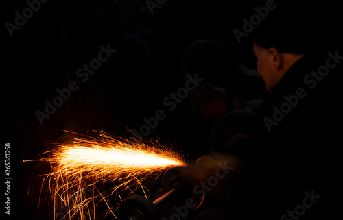 Fire sparks on a black background during workers sharpen a knife.