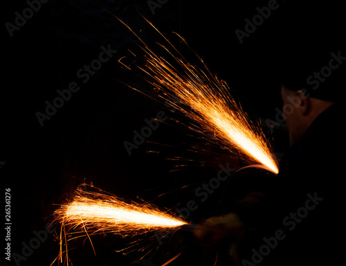 Fire sparks on a black background during workers sharpen a knife.
