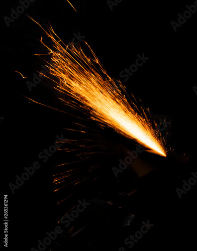 Fire sparks on a black background during workers sharpen a knife.