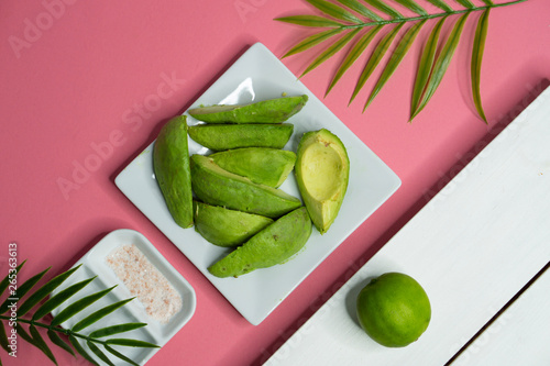 Avocados andpink himalayan salt with palm fronds in a top down flat lay - super foods in a pink and green design  photo