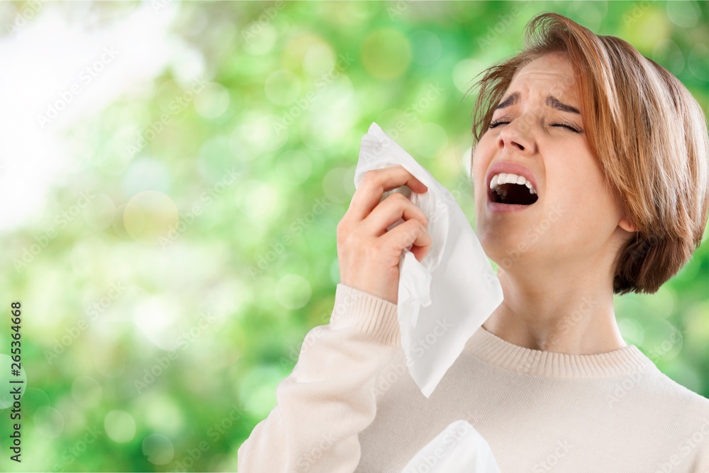 Ill woman with napkin sneezing