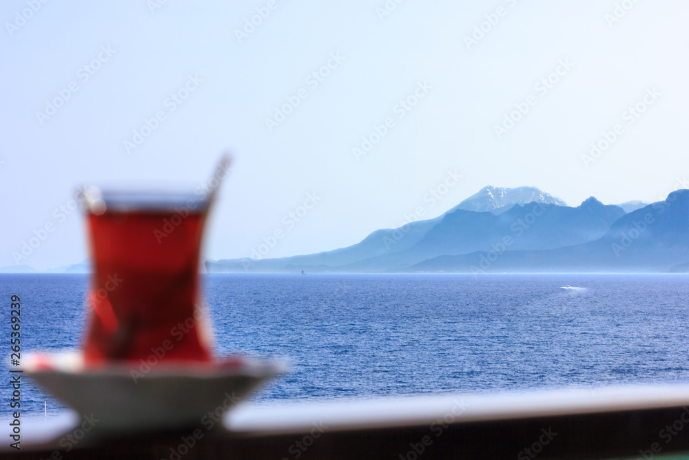 Turkish black tea in traditional glass on background of blue Mediterranean sea Turkish black tea in traditional glass on background of blue Mediterranean sea