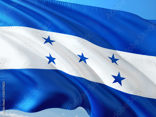Flag of Honduras waving in the wind against deep blue sky. High quality fabric.