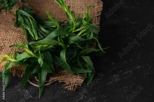 Bundle of fresh tarragon (estragon) isolated on dark stone background. Selective focus, Close up, Macro
