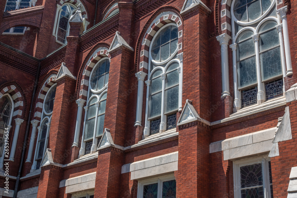 Detail exterior architecture of red brick Gothic Revival church with arched windows, horizontal aspect