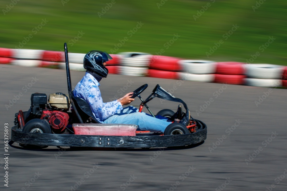 Man behind the wheel of a kart. Karting on racing round in the open air. Man rides on a kart with high speed.