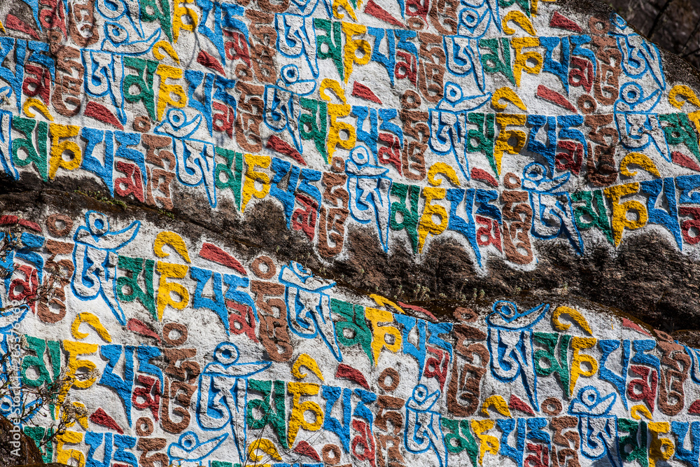 Colourful Tibetan script on a boulder in the Nepalese Himalayas; Nepal Colourful Tibetan script on a boulder in the Nepalese Himalayas; Nepal