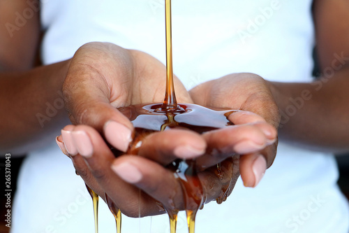Black African hands cupped holding pouring honey for beauty purposes