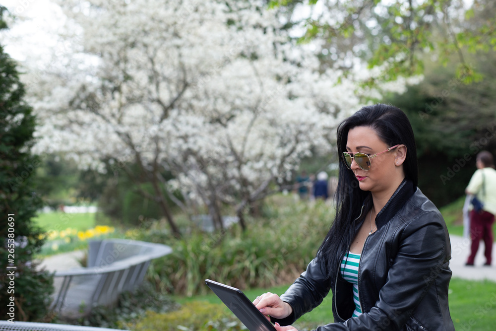.Brunette sitting on a street bench and smiling works on a computer .Brunette sitting on a street bench and smiling works on a computer