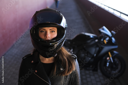 Attractive serious woman is standing next to her motobike. She is wearing a helmet. © Fxquadro