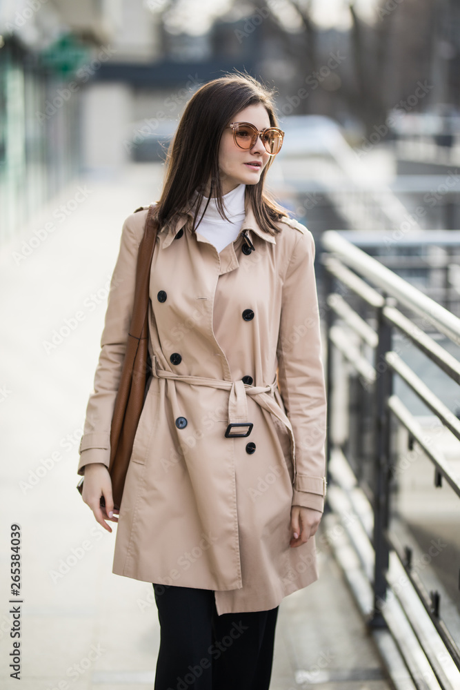 Beautiful brunette young woman in nice coat and sunglasses on urban background. Beautiful brunette young woman in nice coat and sunglasses on urban background.